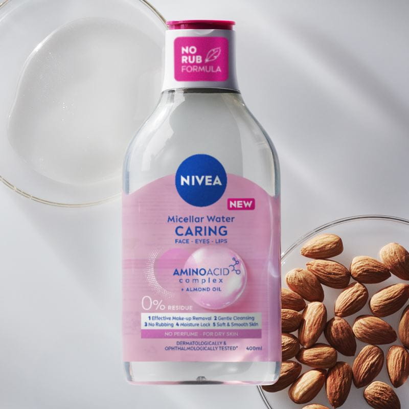 A bottle of NIVEA Micellar Water for Dry Skin lays on a red bubble textured background.