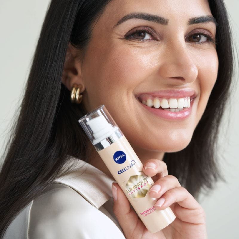 A woman holding a NIVEA LUMINOUS630 product while smiling
