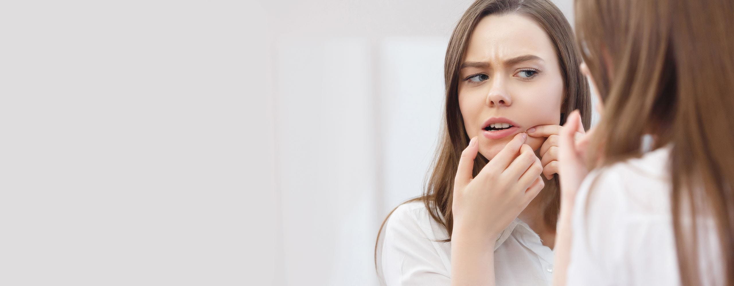 mujer sacando un grano de su rostro