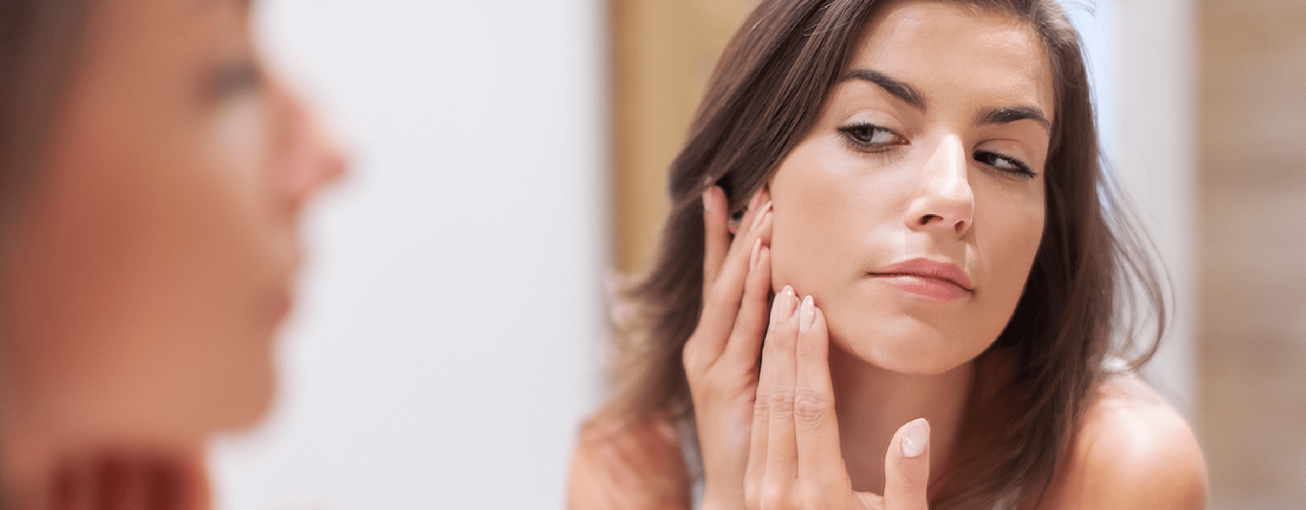 Persona tocandose un grano del rostro