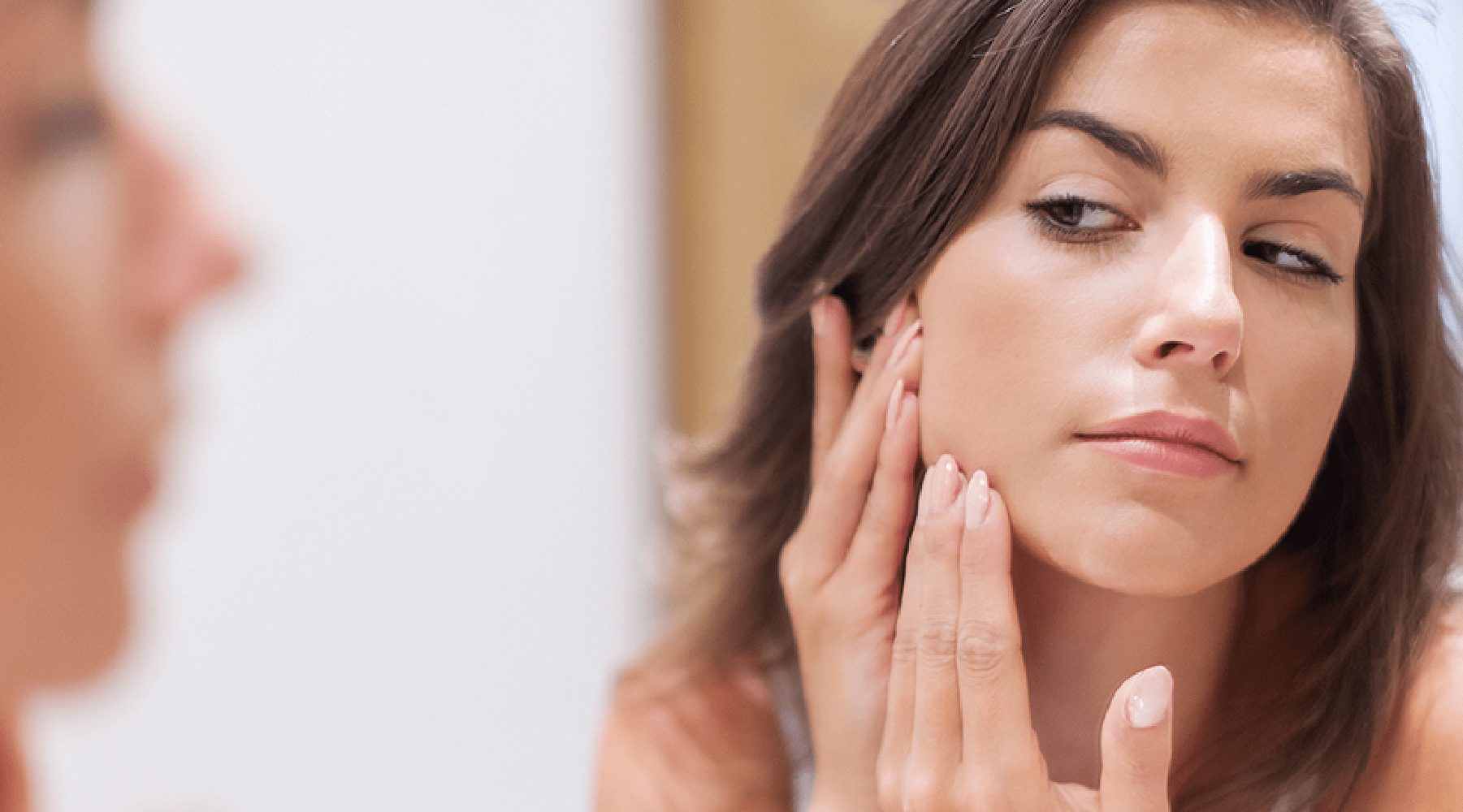 Persona tocandose un grano del rostro