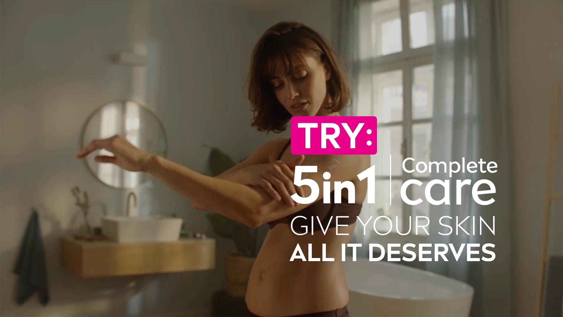 View of a female model touching her left arm with the text TRY: 5in1 Complete Care Give Your Skin All It Deserves in white font displayed over top.