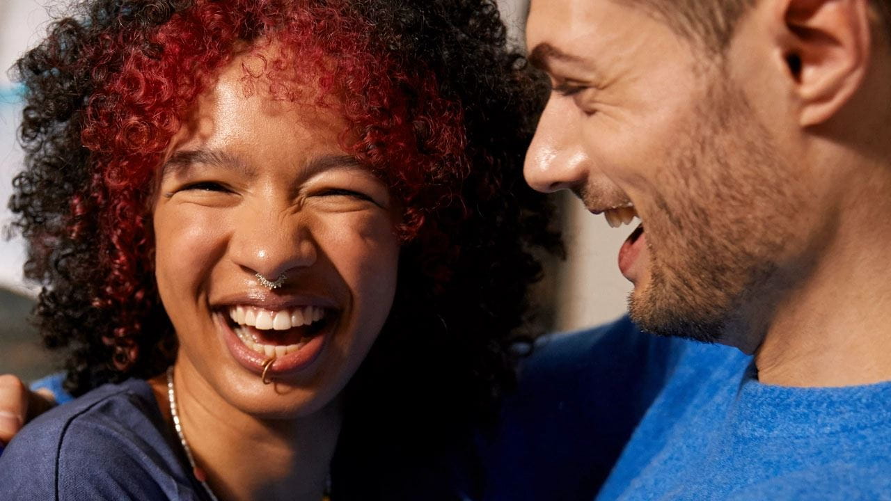 Deux personnes sourient et rient ensemble un à côté de l'autre.