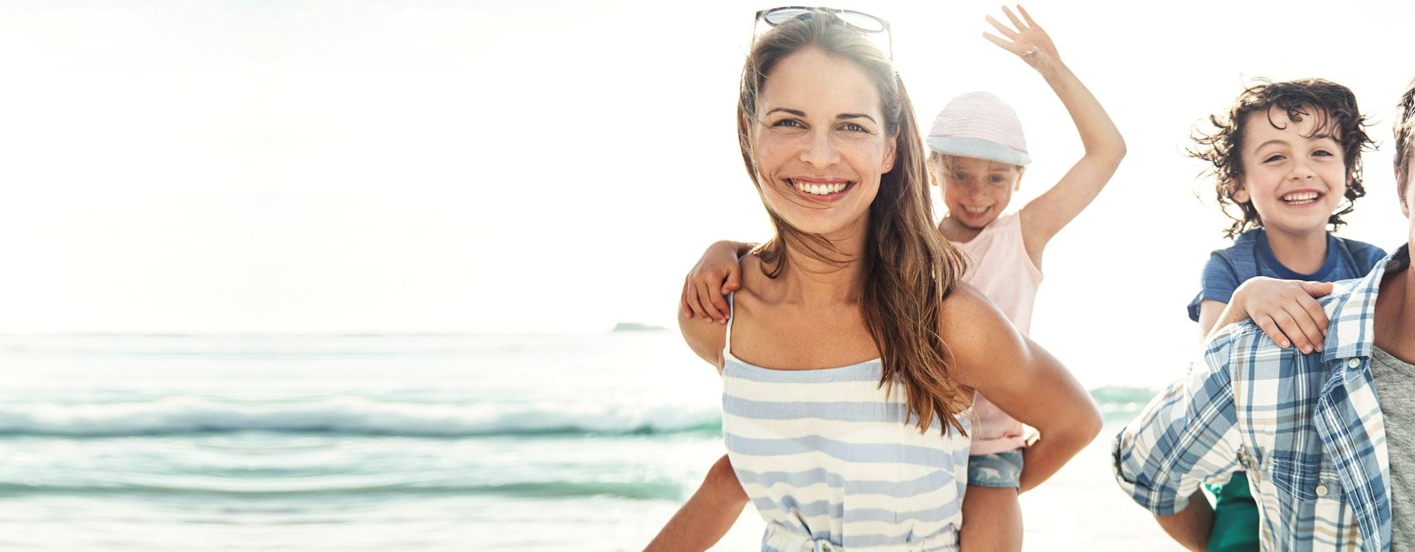 Parents qui portent enfants sur leur dots à la plage