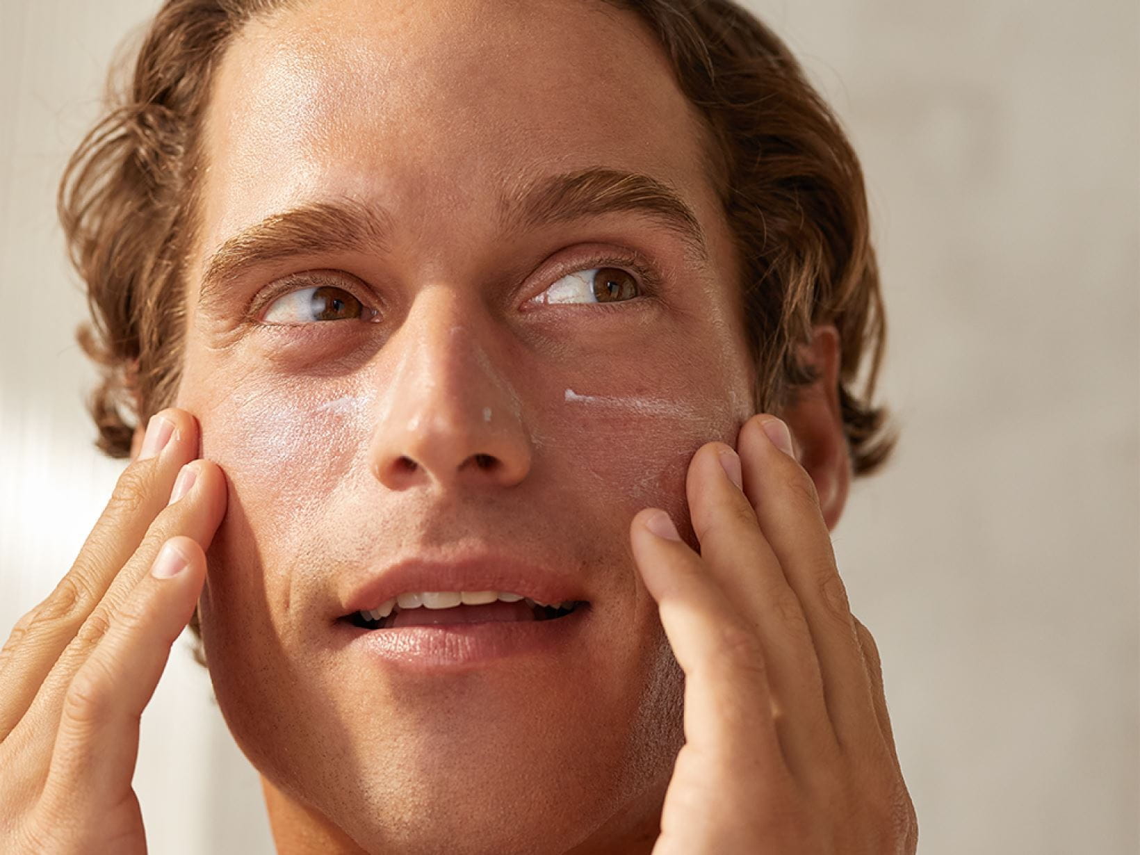 Un homme appliquant de la crème sur son visage