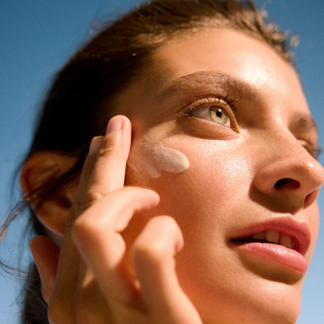 Frau trägt Sonnencreme auf ihr Gesicht auf
