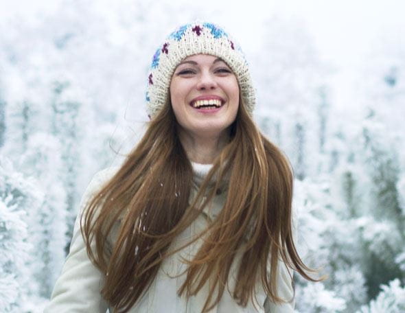 Frau steht im Schnee und lacht