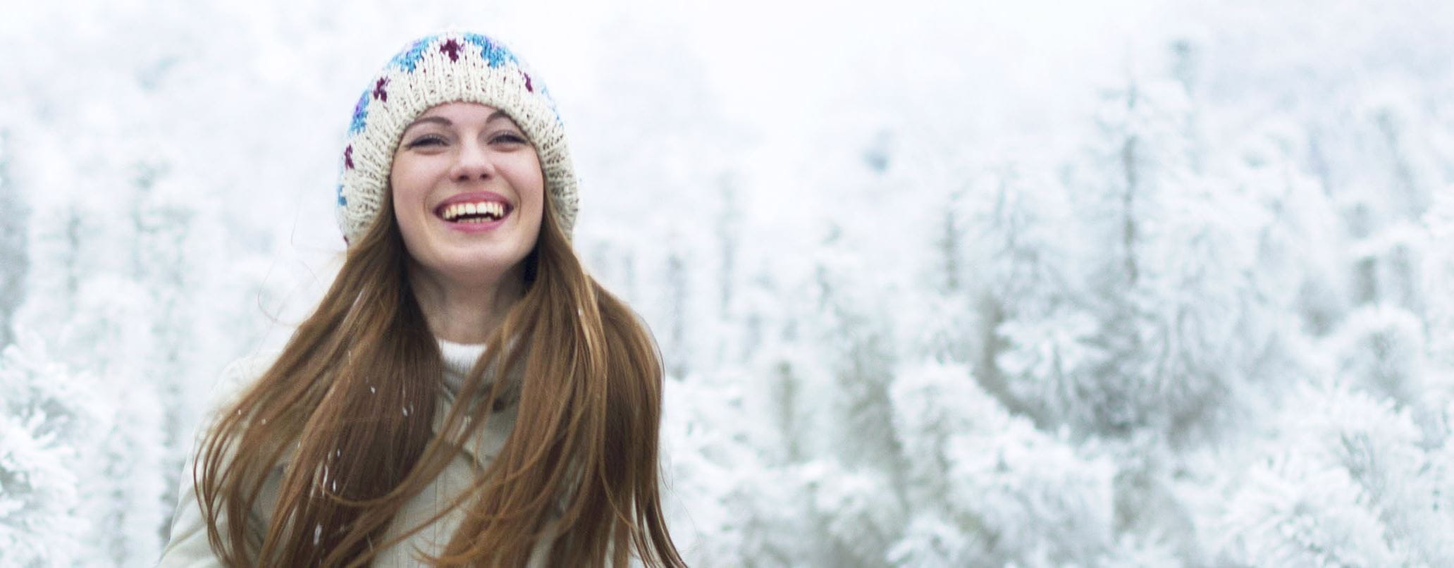 Frau steht im Schnee und lacht
