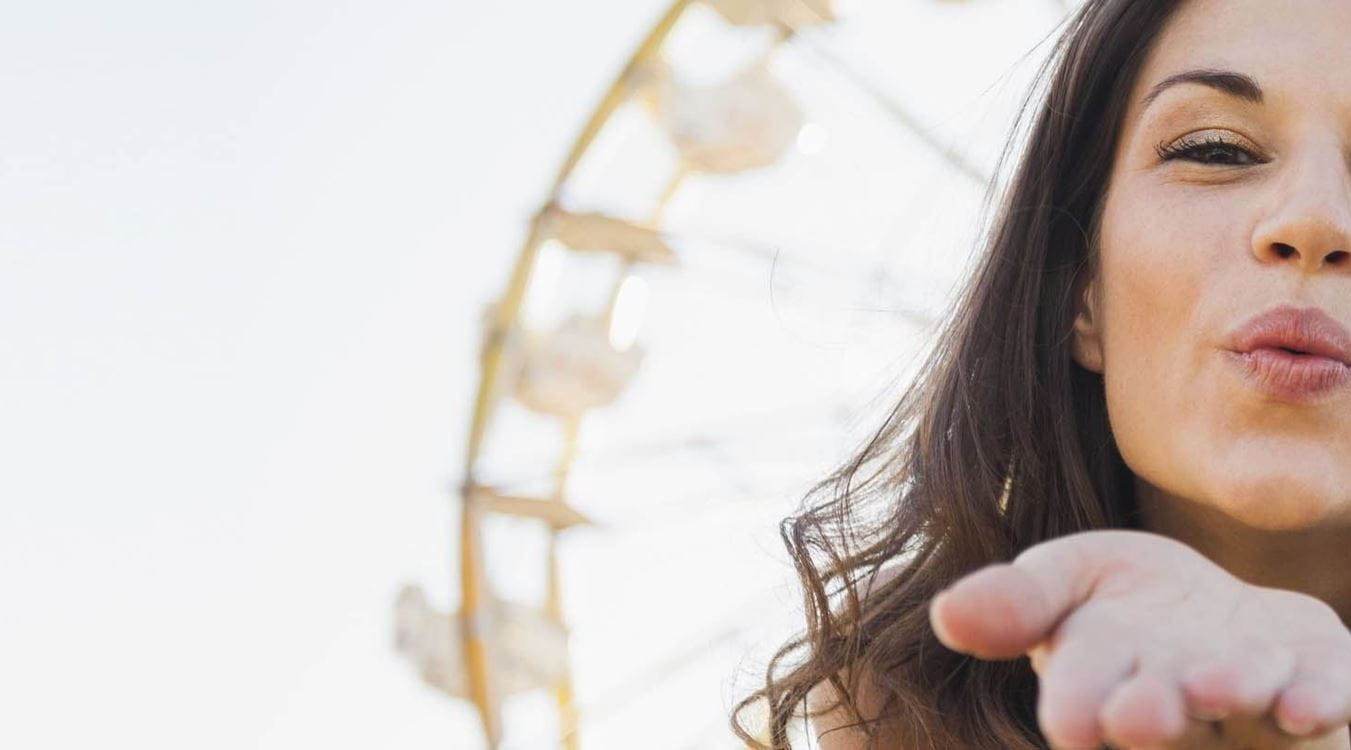 Frau macht Kussmund und hält sich die Augen zu