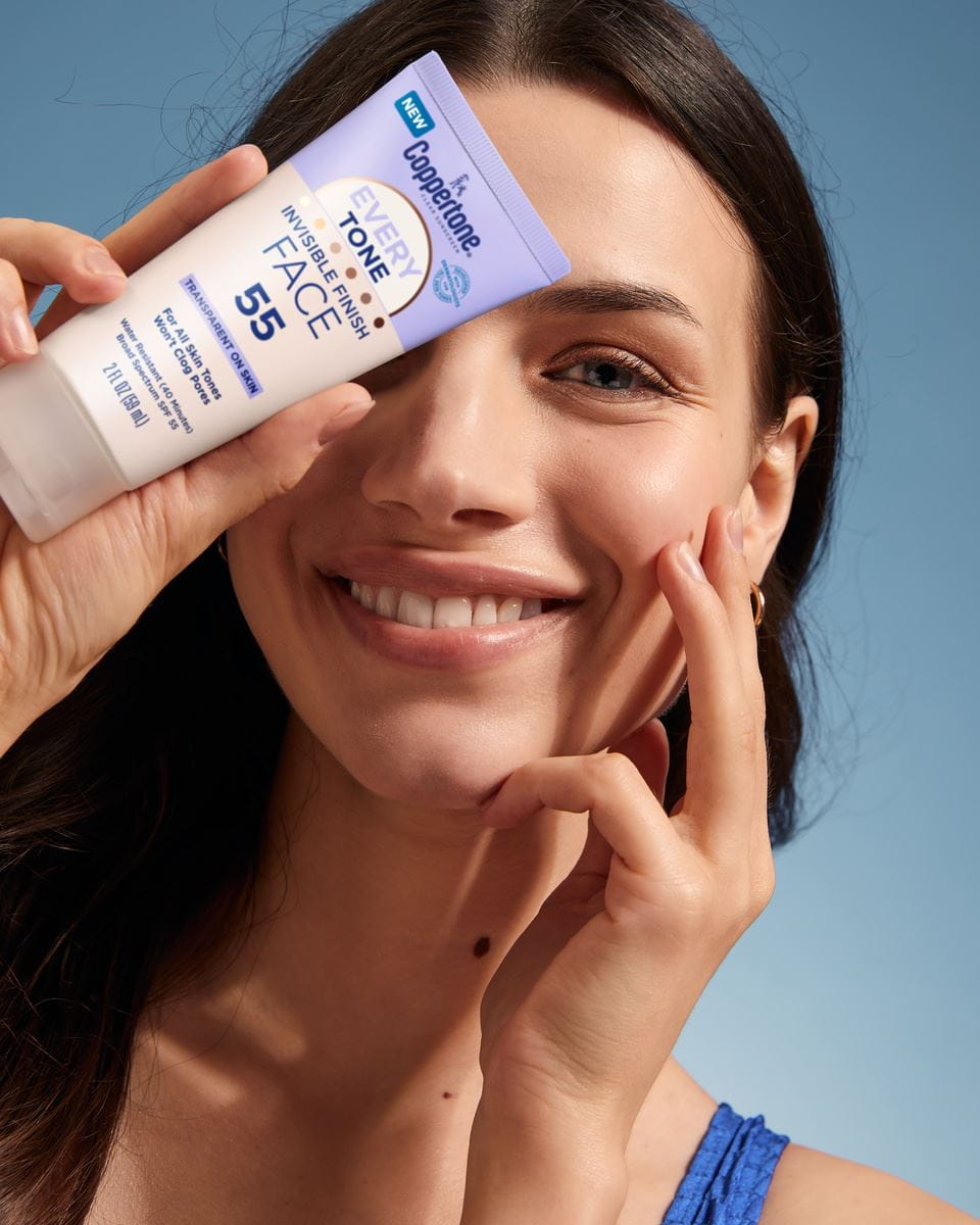 woman holding sunscreen smiling