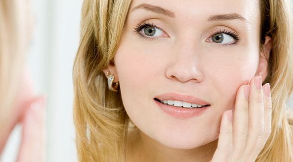Femme avec bijoux se touche le visage