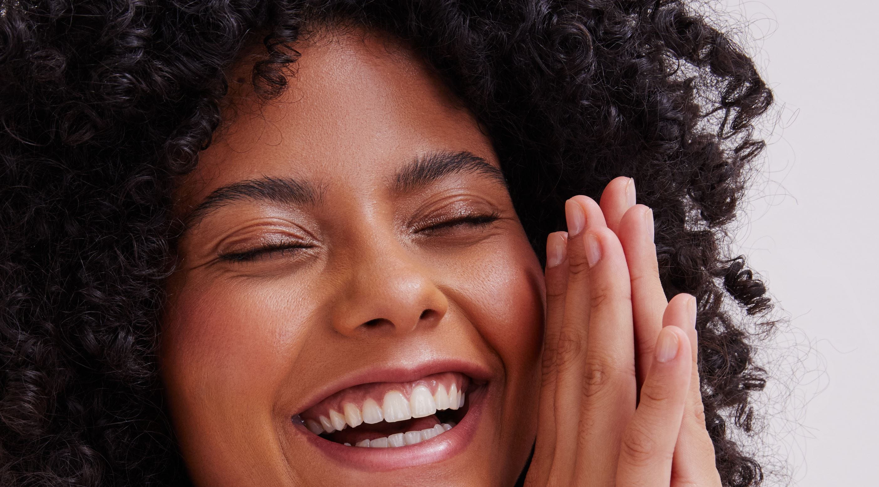 ragazza con i capelli ricci con in mano una crema per le mani Nivea