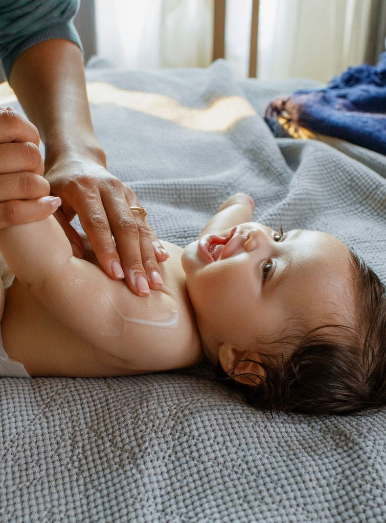 Mutter trägt Nivea-Babycreme auf ihr Baby auf