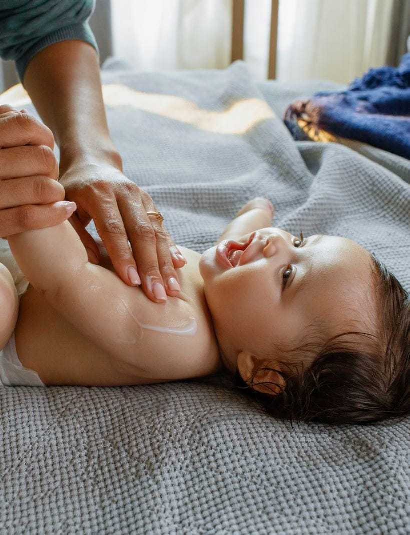 Mutter trägt Nivea-Babycreme auf ihr Baby auf