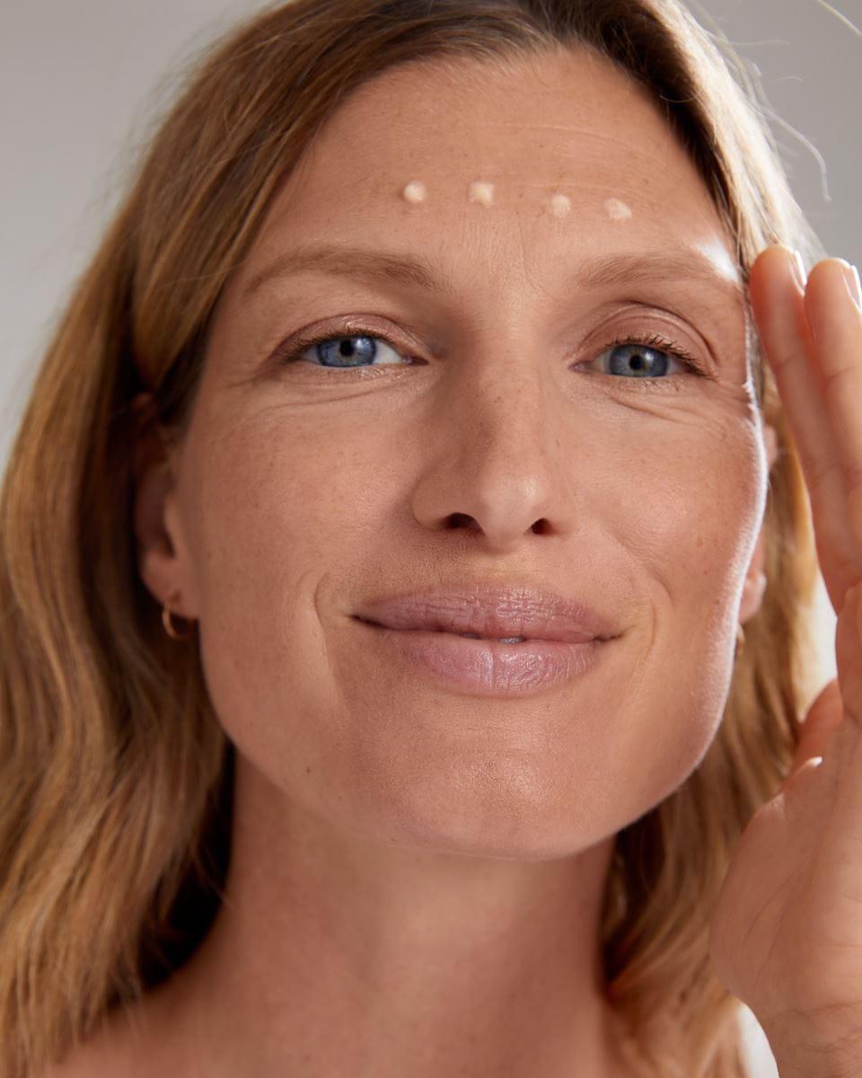Frau, die Nivea-Gesichtscreme auf ihre Stirn aufträgt