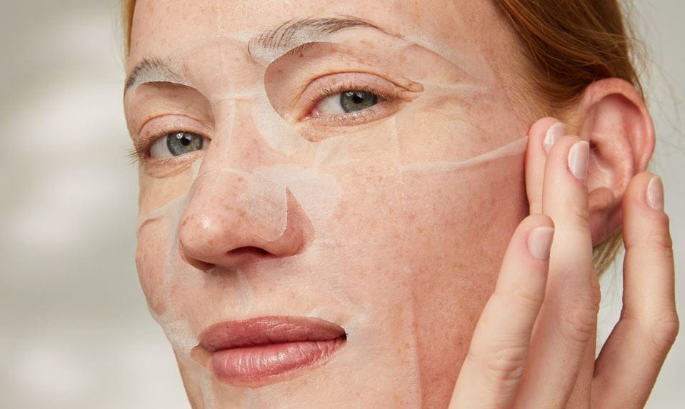 Frau trägt eine feuchtigkeitsspendende Gesichtsmaske auf