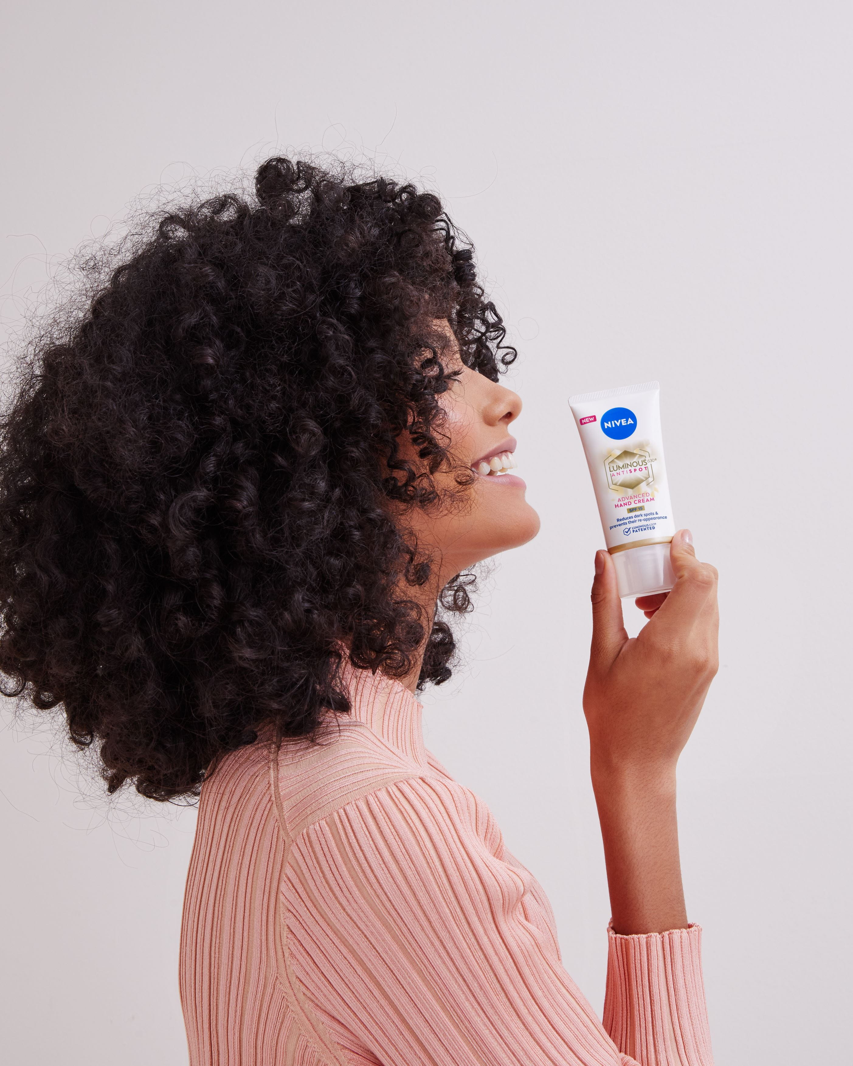 Mädchen mit lockigem Haar, das eine Nivea-Handcreme hält
