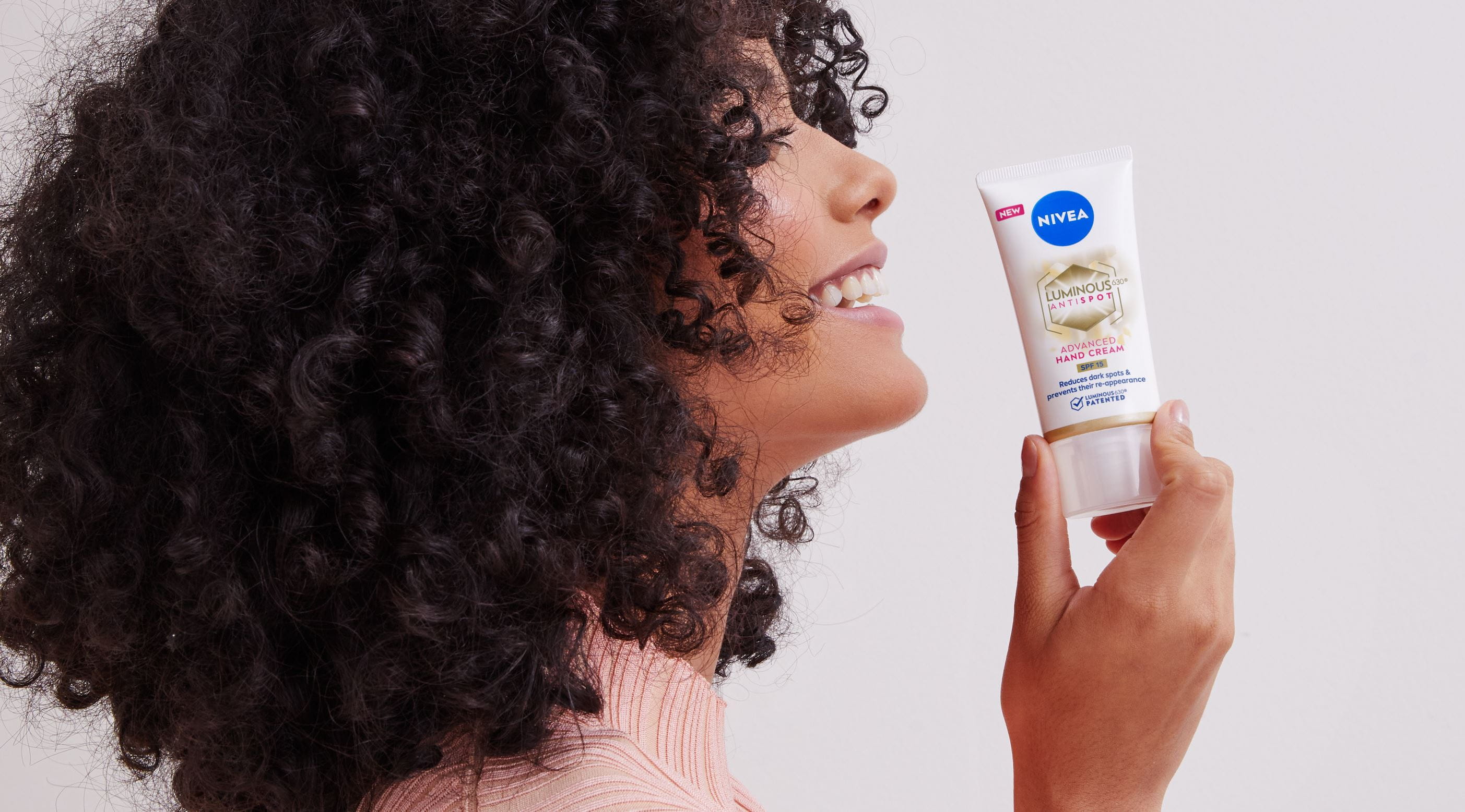 Mädchen mit lockigem Haar, das eine Nivea-Handcreme hält