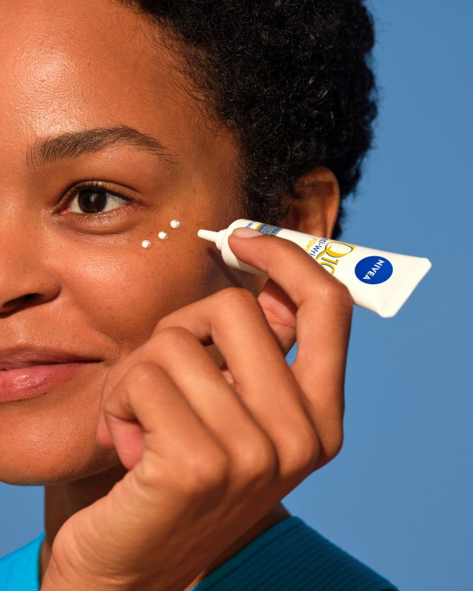 tânără care aplică crema de ochi Nivea Q10