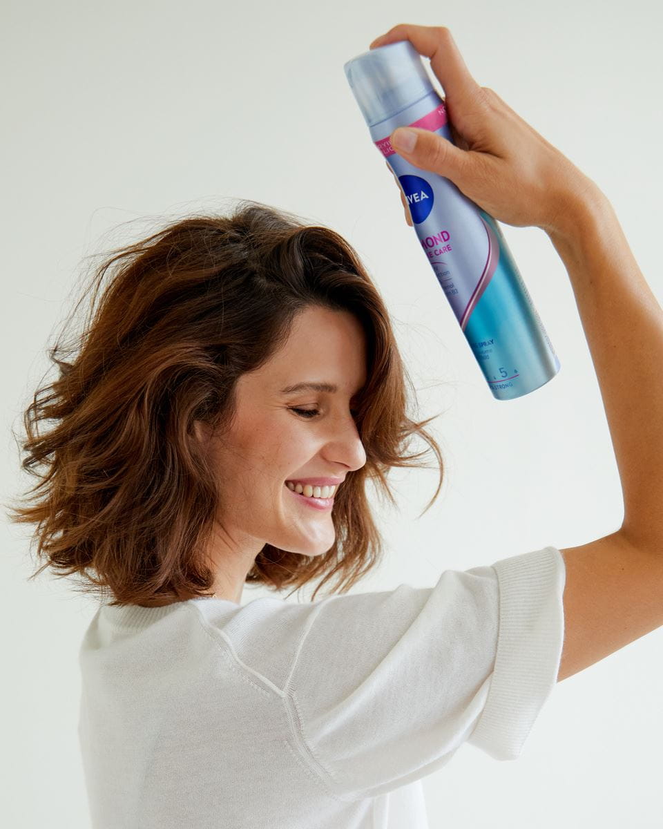 Junge Frau benutzt Nivea-Haarspray