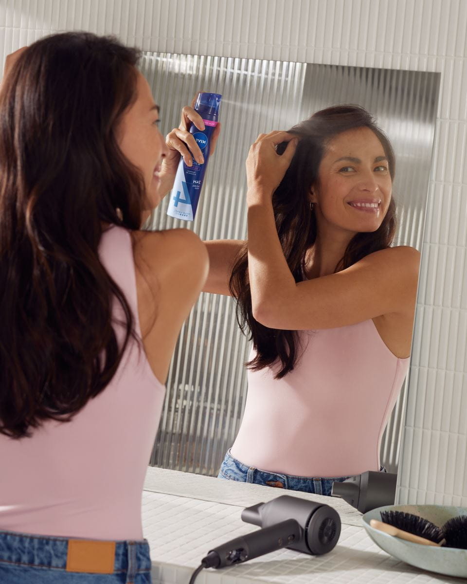 Junge Frau stylt ihre Haare mit Nivea-Haarspray