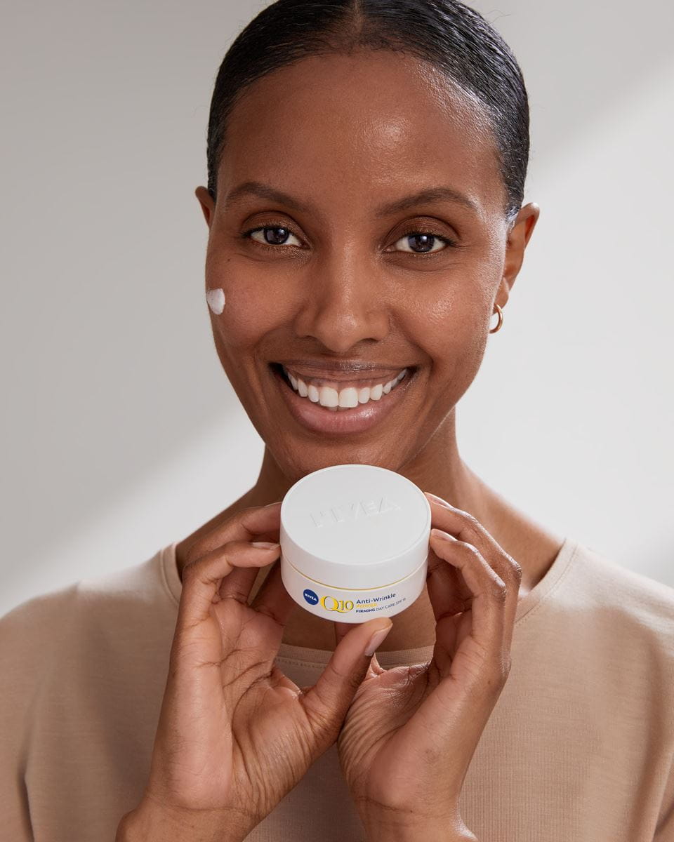 kobieta trzyma krem ​​do twarzy Nivea Q10