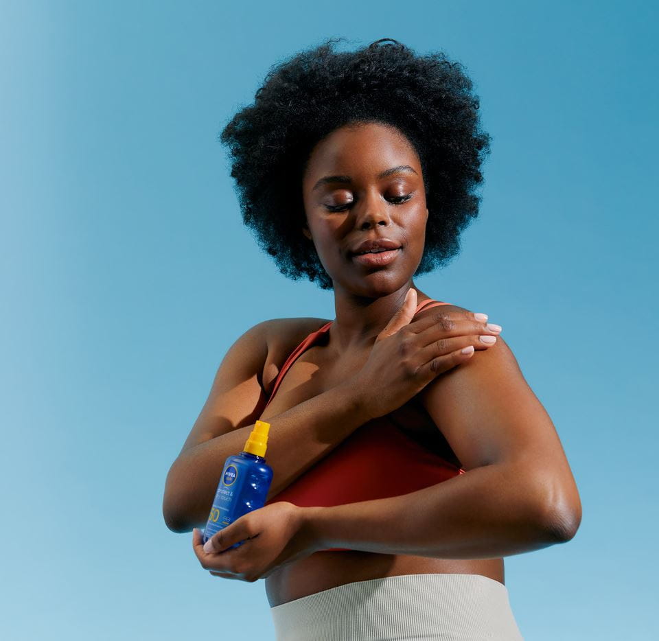 Afro μαλλιά γυναίκα που εφαρμόζει κρέμα Nivea SPF