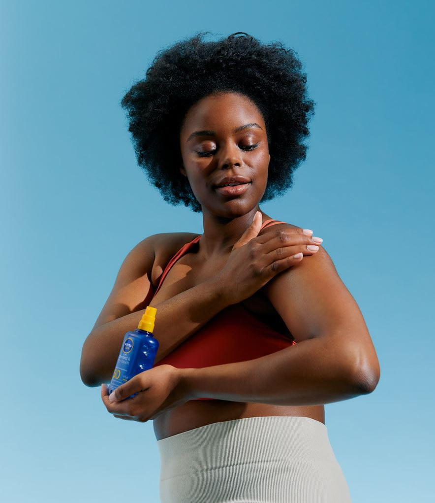 Chica aplicando Nivea Sun Protect & Dry Touch Spray