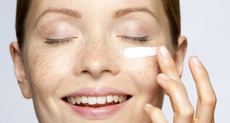 femeie punându-și cremă pe față