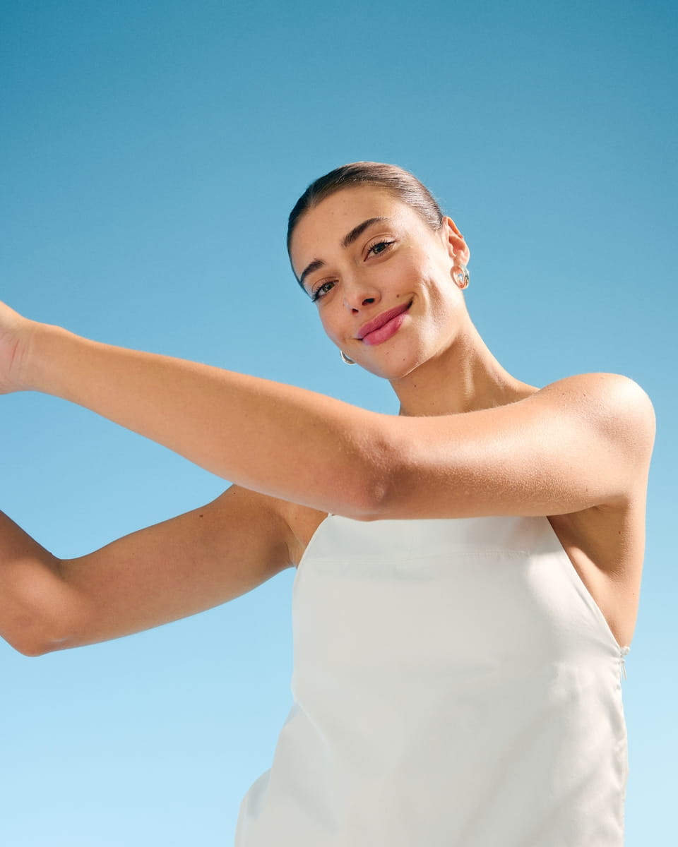 Woman with white shirt smiling under the blue sky
