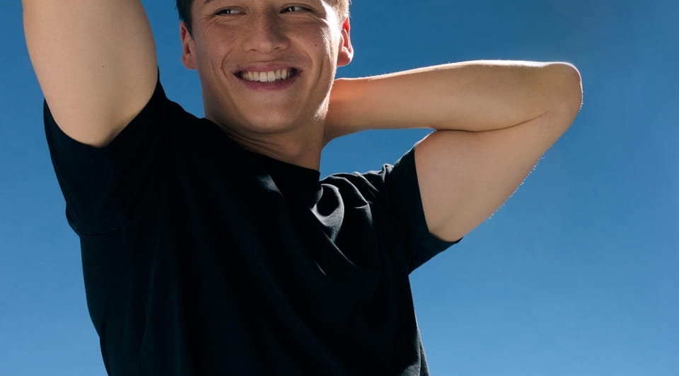 Men with black shirt smiling under the blue sky