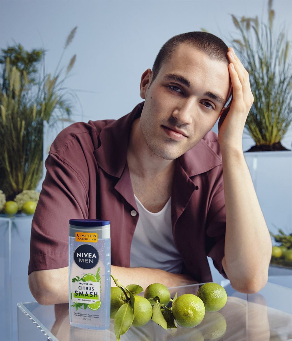 Young man resting his head on his hand, with plants in the background
