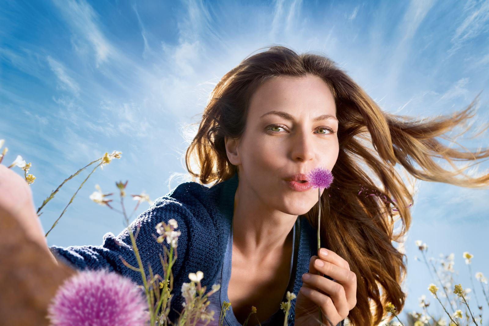 woman blowing purple flower