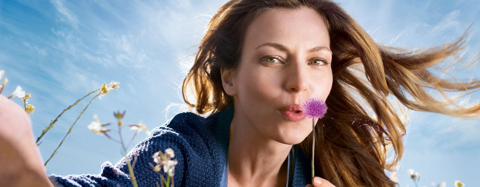 woman blowing purple flower