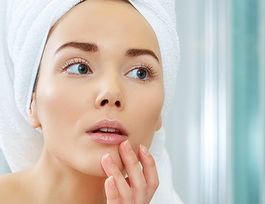 woman with white towel touching her face