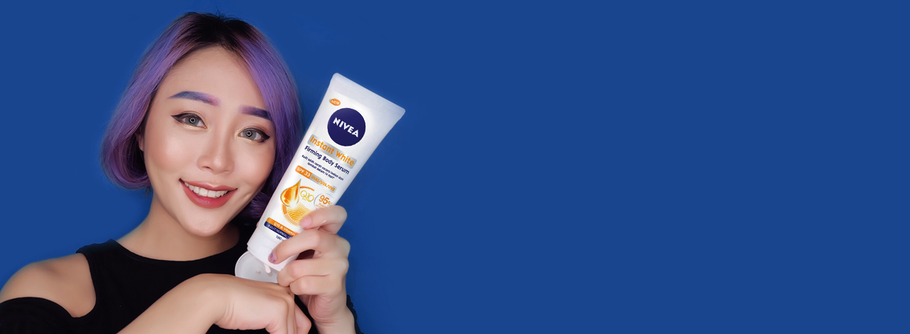 woman with purple hair applying NIVEA body serum