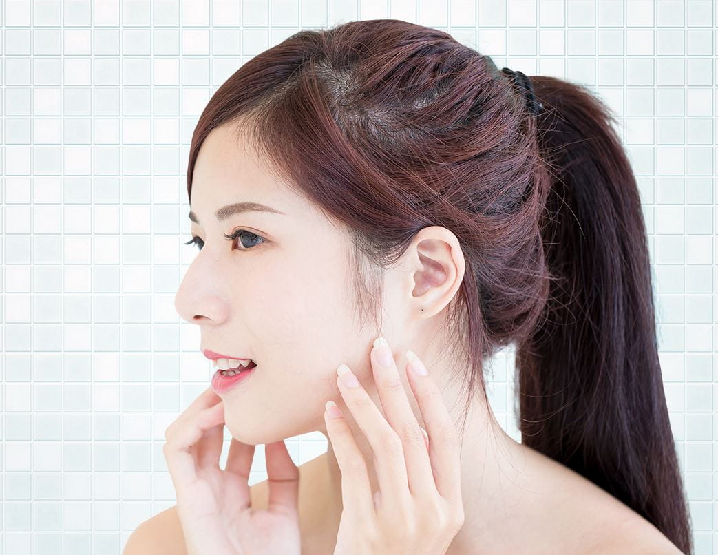 woman with burgundy hair touching her cheeks