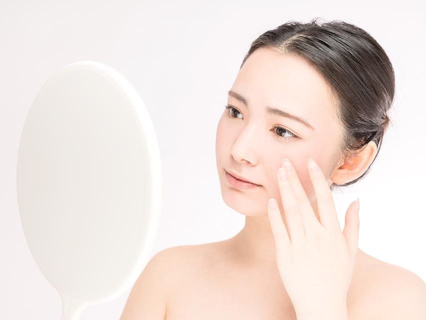 woman looking in the mirror and touching her face