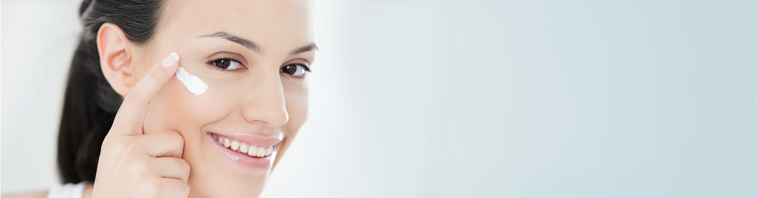 woman smiling and applying cream in her face