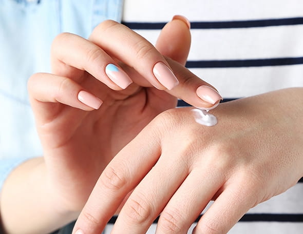 manicured fingers applying cream on hands