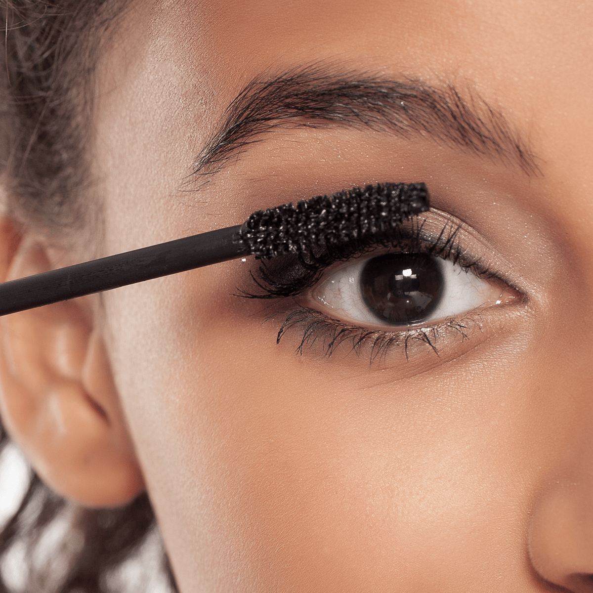 Lady doing makeup to her eye lashes