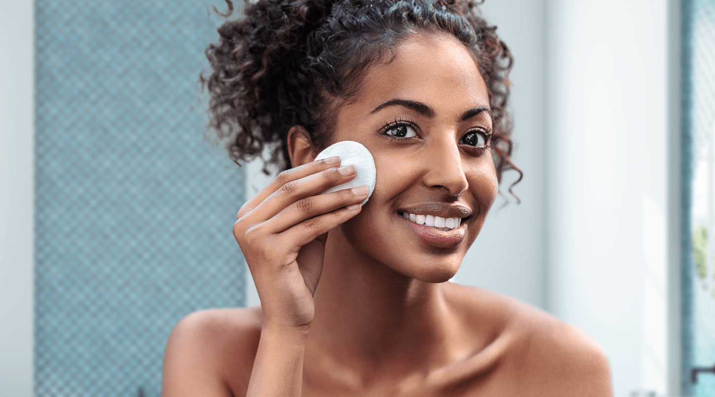 Woman cleaning her face with micellar water and face scrub