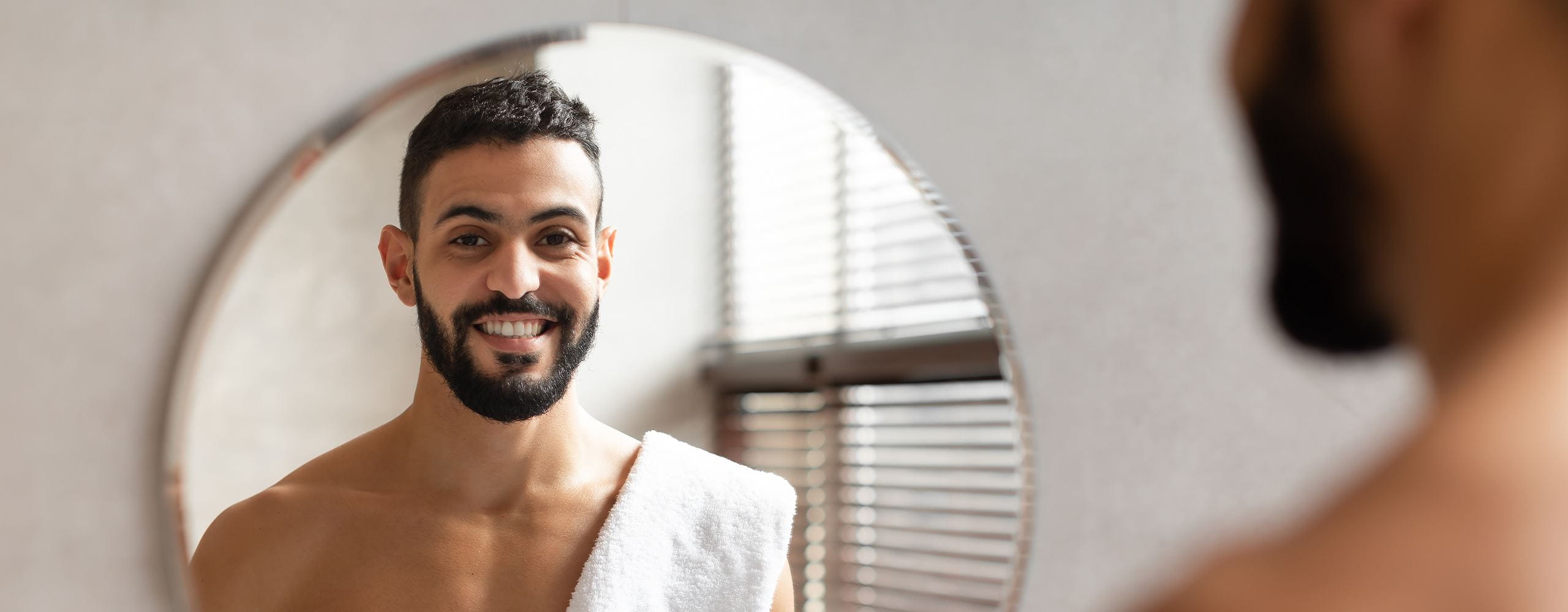 A Man Smiling while looking at his reflection in the mirror