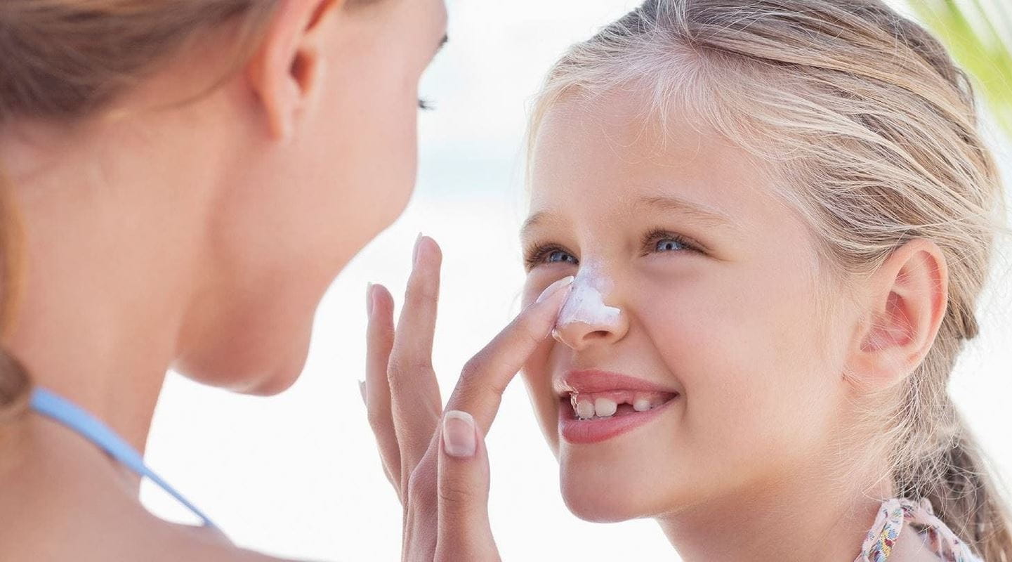 أم تضع كريم الوقاية من الشمس على وجه ابنتها بشكل لطيف