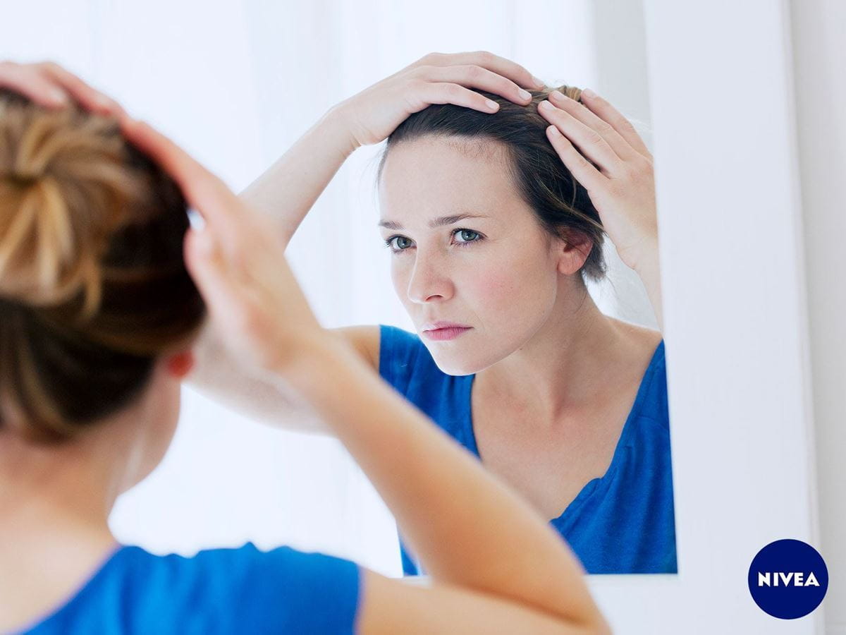Roos in je haar vrouw die in spiegel kijkt - NIVEA