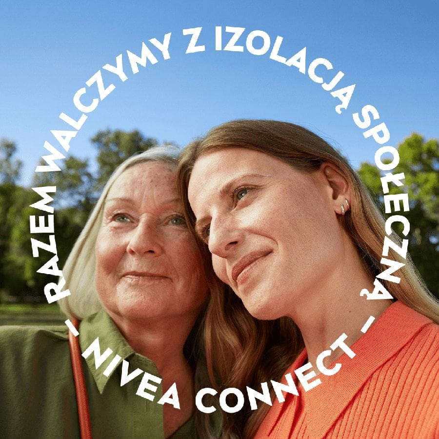 Two women looking off-camera with a blue sky and trees in the background.