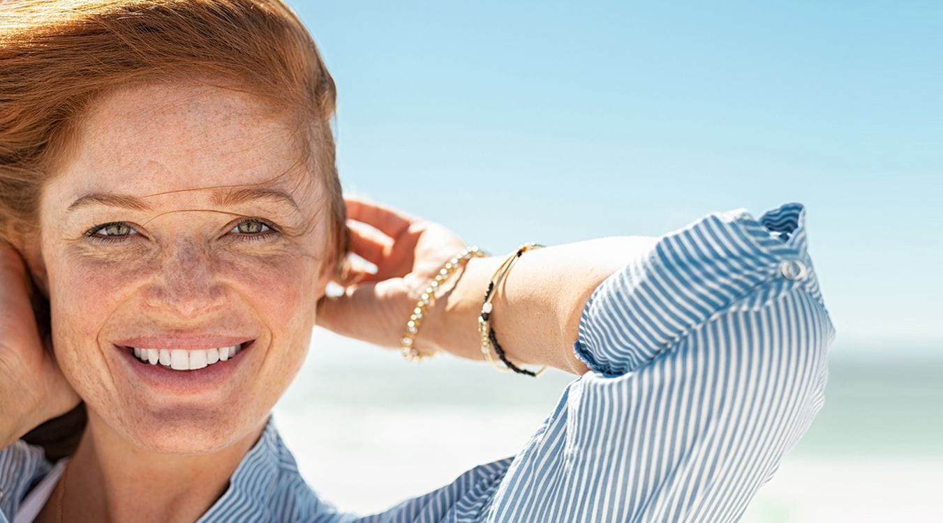 Mulher sorridente na praia com rosto cuidado