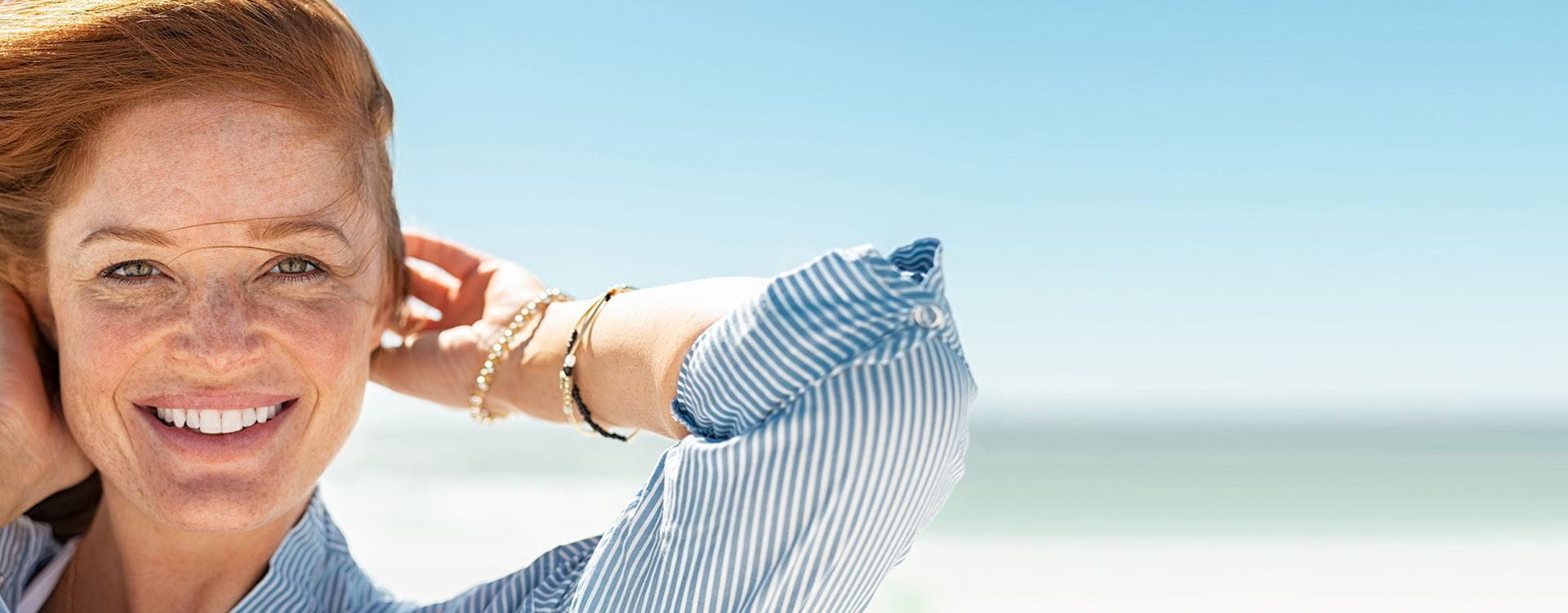 Mulher sorridente na praia com rosto cuidado