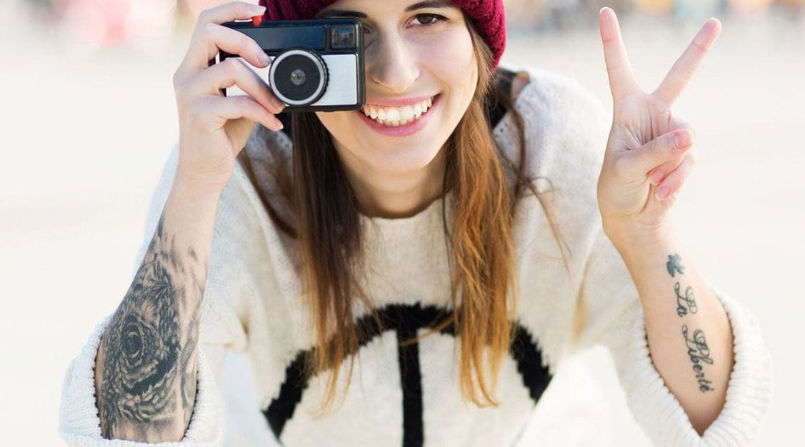 Jovem com tatuagens e câmara fotográfica