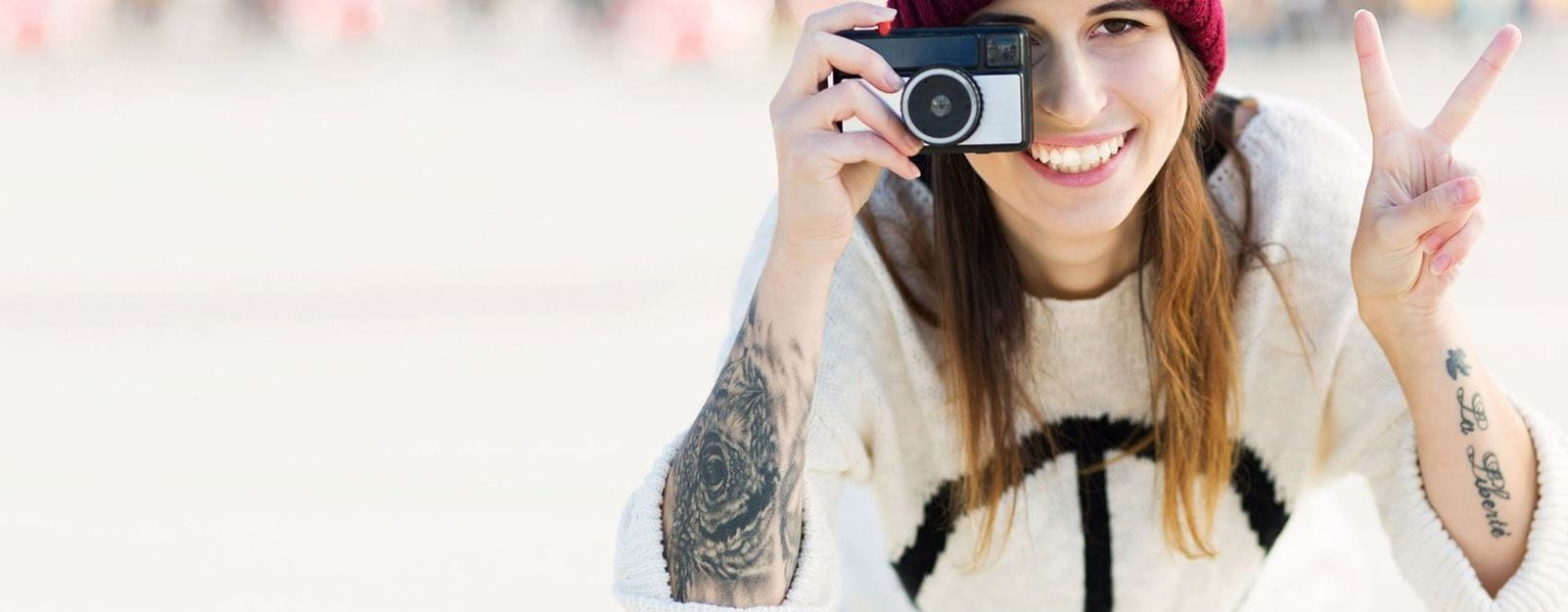 Jovem com tatuagens e câmara fotográfica